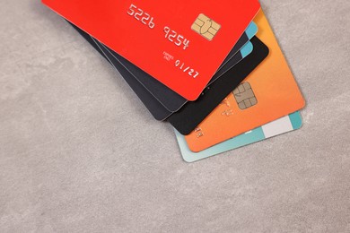 Photo of Pile of different credit cards on grey table, top view. Space for text