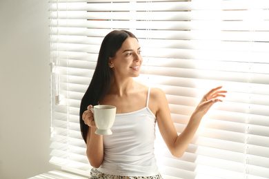 Young woman with cup of tea near window. Lazy morning