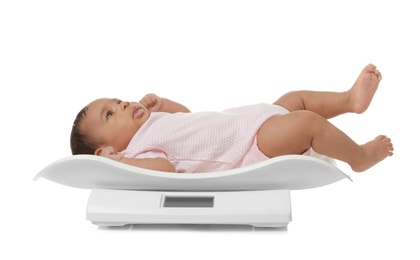 Photo of African-American baby lying on scales against white background