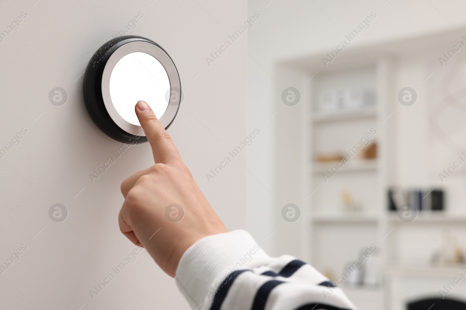 Photo of Woman adjusting thermostat on white wall indoors, closeup. Smart home system