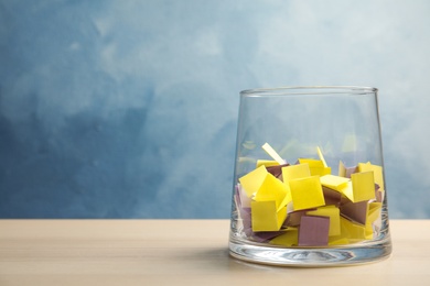 Photo of Colorful paper pieces for lottery in glass vase on table. Space for text