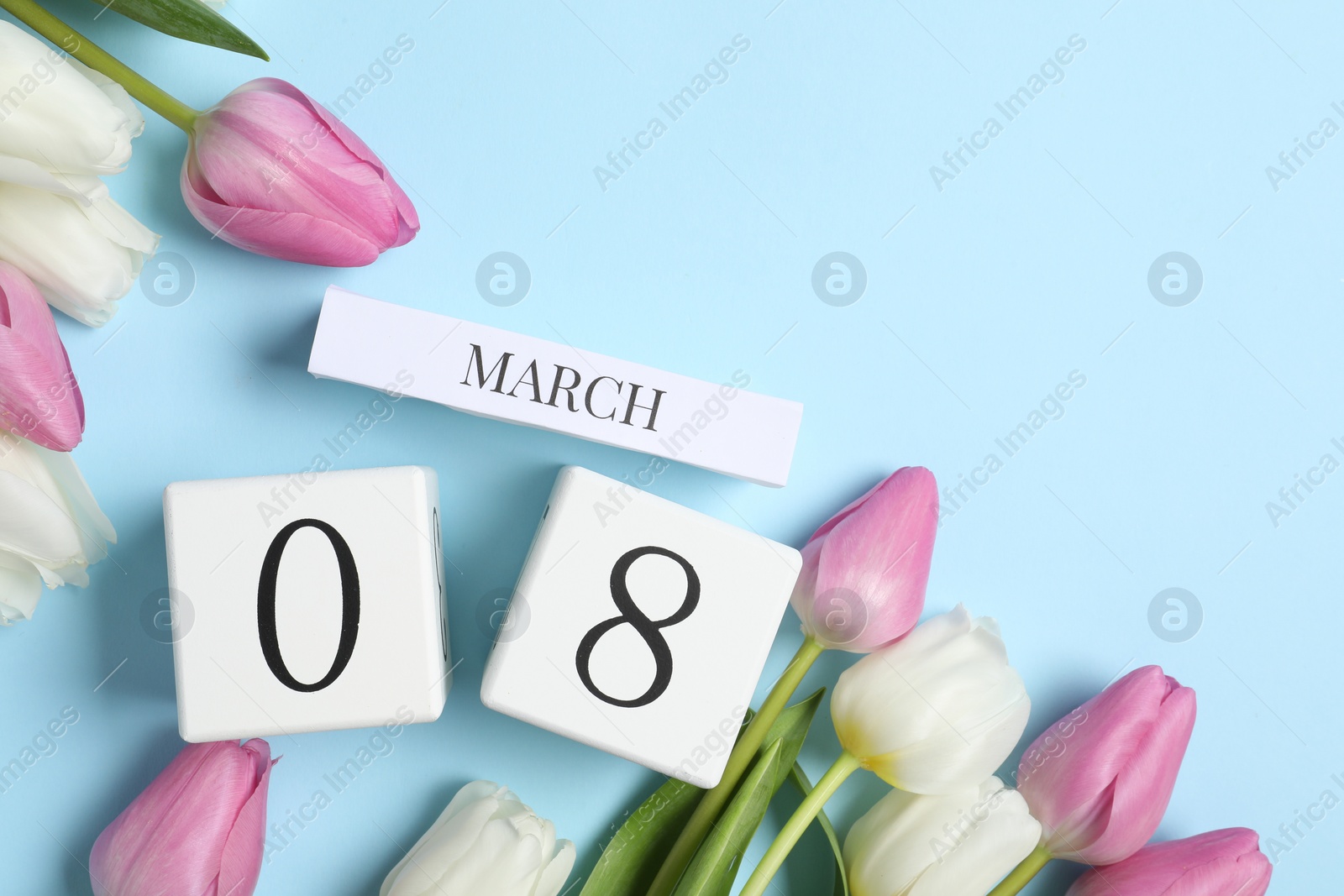 Photo of International Women's day - 8th of March. Block calendar and beautiful tulips on light blue background, flat lay. Space for text