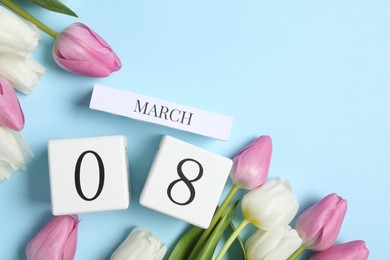 Photo of International Women's day - 8th of March. Block calendar and beautiful tulips on light blue background, flat lay. Space for text