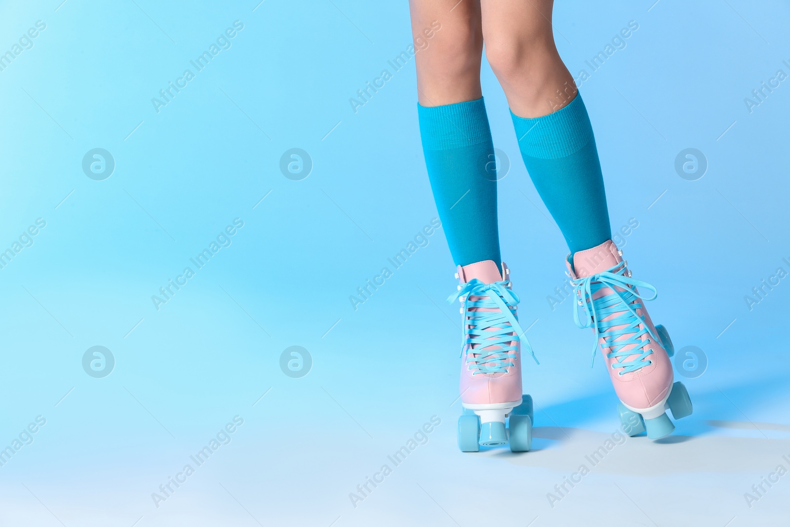 Photo of Woman with vintage roller skates on color background, closeup. Space for text