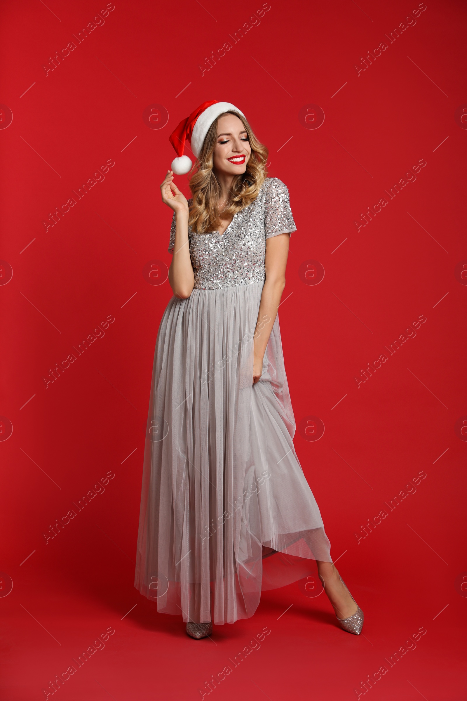Photo of Happy young woman wearing Santa hat on red background. Christmas celebration