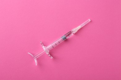 Photo of Injection cosmetology. One medical syringe on pink background, top view