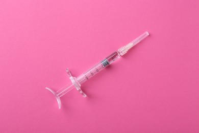 Injection cosmetology. One medical syringe on pink background, top view