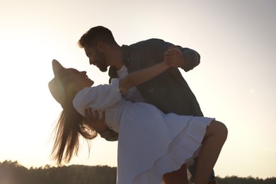 Happy couple dancing near river at sunset