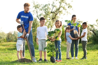 Kids planting trees with volunteers in park