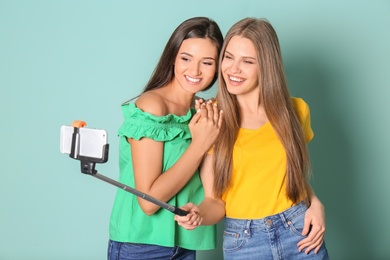 Photo of Young beautiful women taking selfie against color background