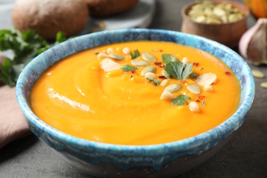 Photo of Delicious pumpkin soup in bowl on table, closeup