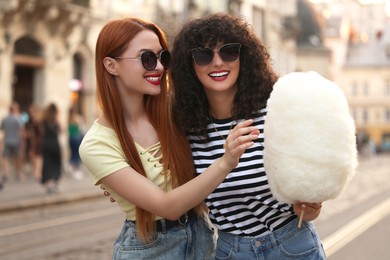 Happy friends with cotton candy on city street