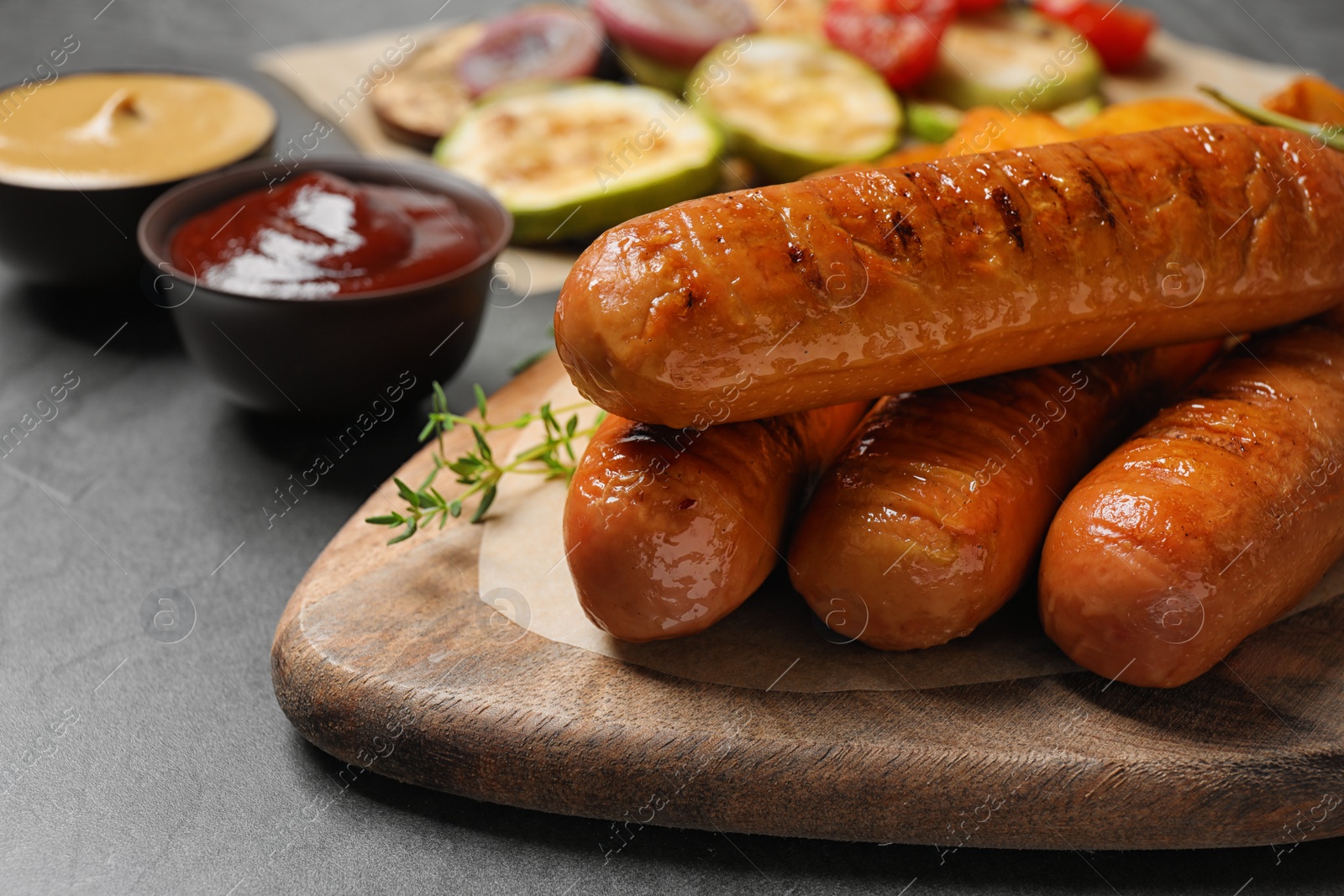 Photo of Delicious grilled sausages with thyme on grey table, closeup. Space for text