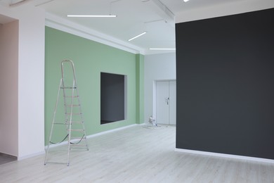 Photo of Empty room with green wall and ladder during repair