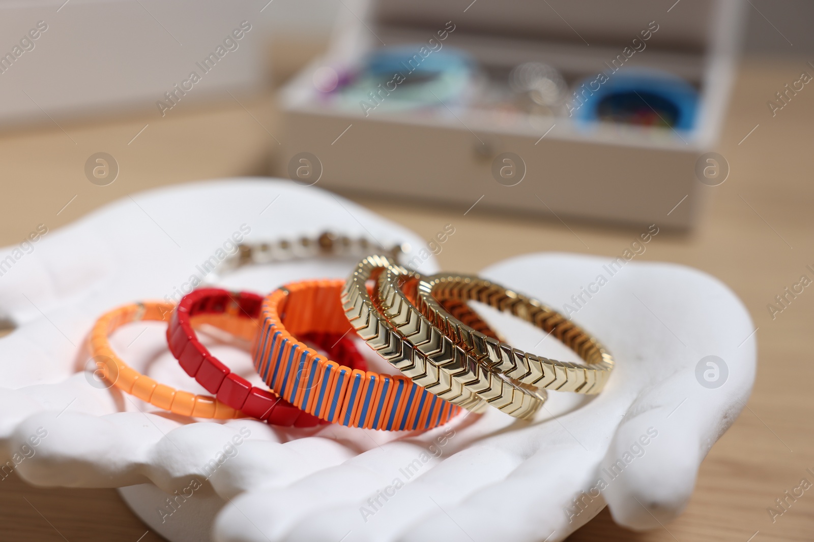 Photo of Ceramic hand stand with many different bracelets on table, closeup