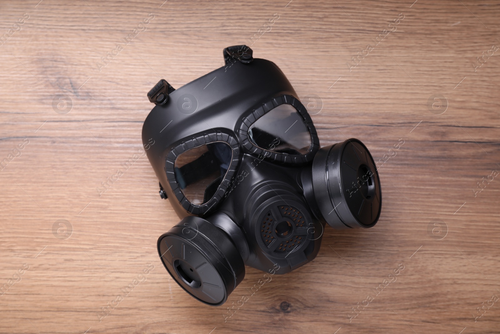 Photo of One gas mask on wooden background, top view