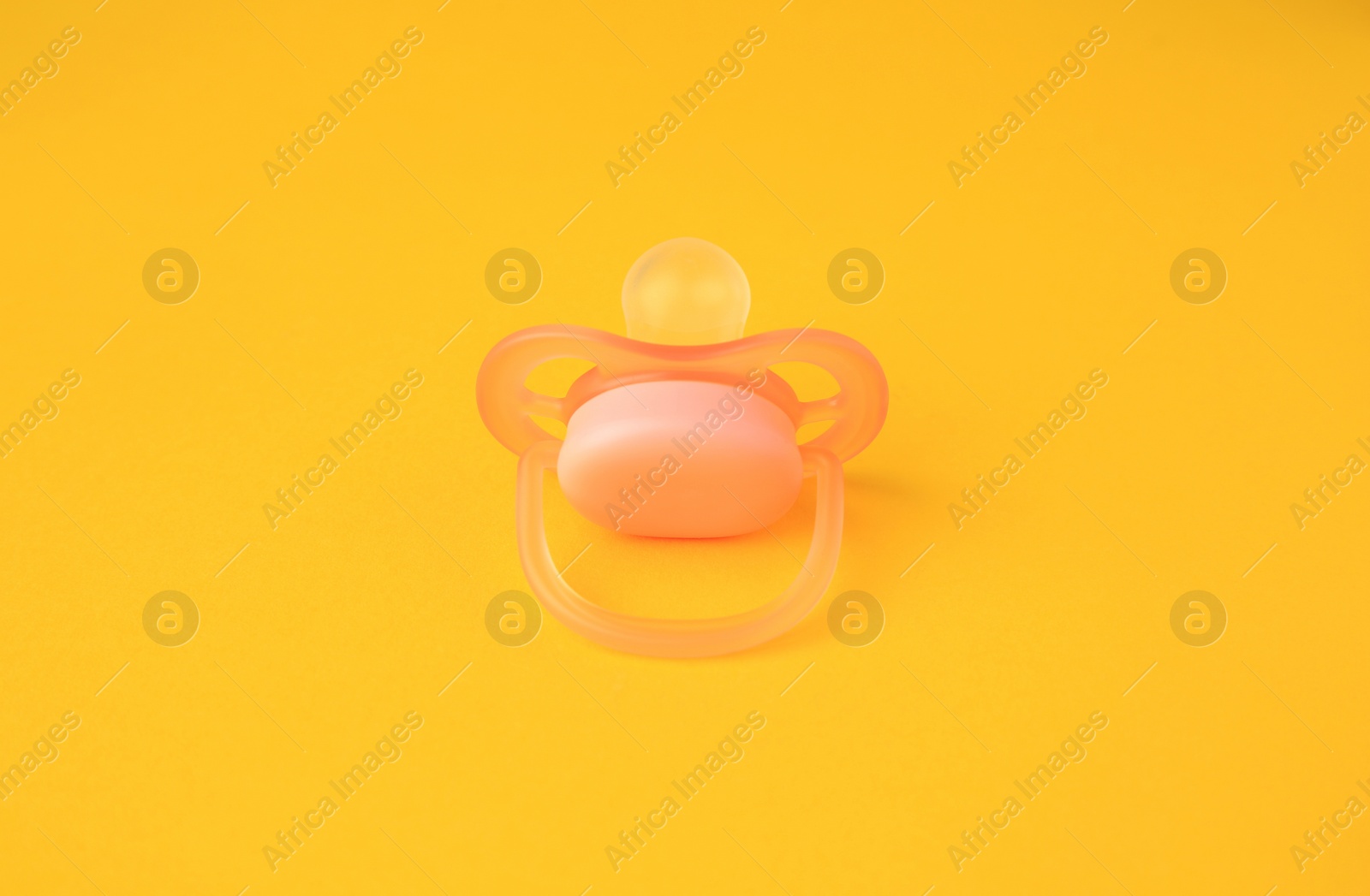 Photo of One new baby pacifier on orange background