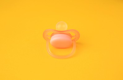 Photo of One new baby pacifier on orange background