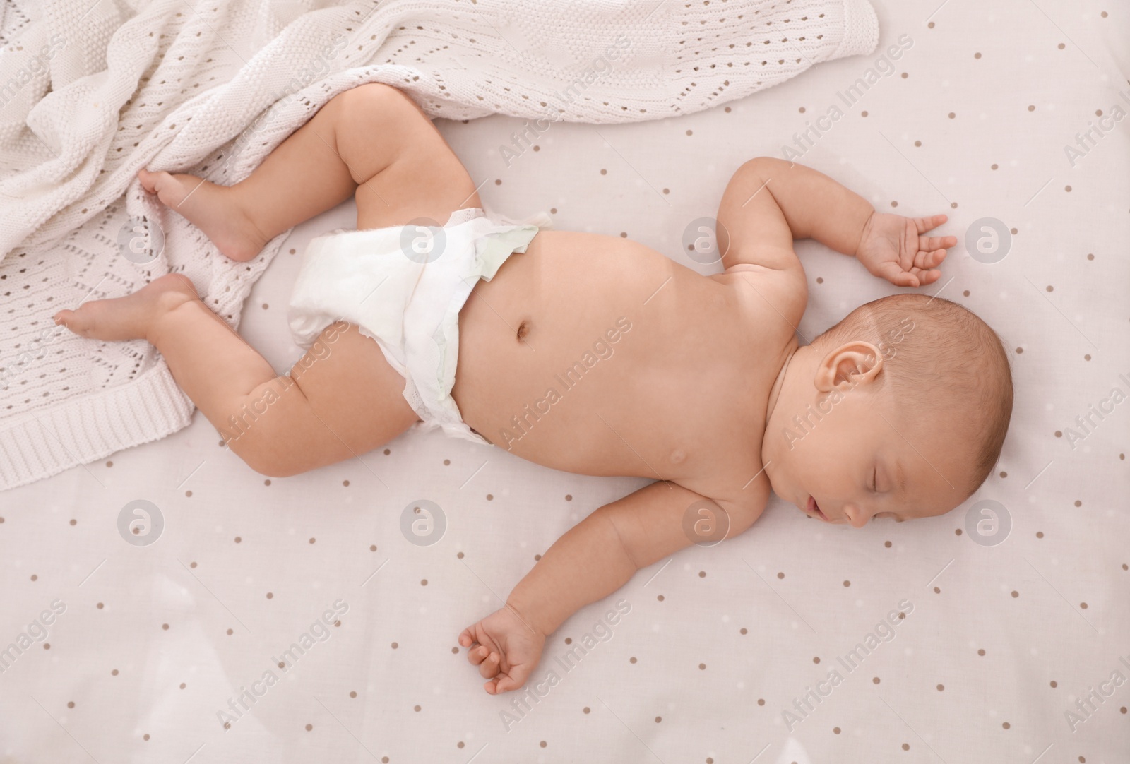 Photo of Cute little baby in diaper sleeping on bed, top view