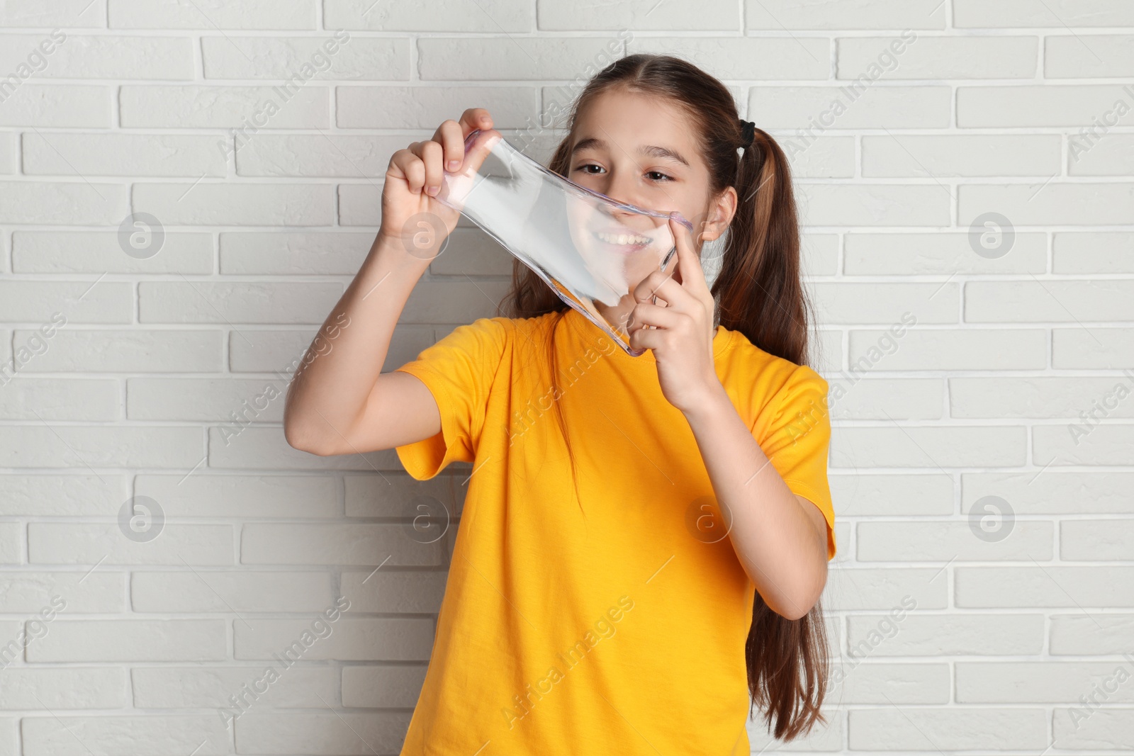 Photo of Preteen girl with slime near white brick wall