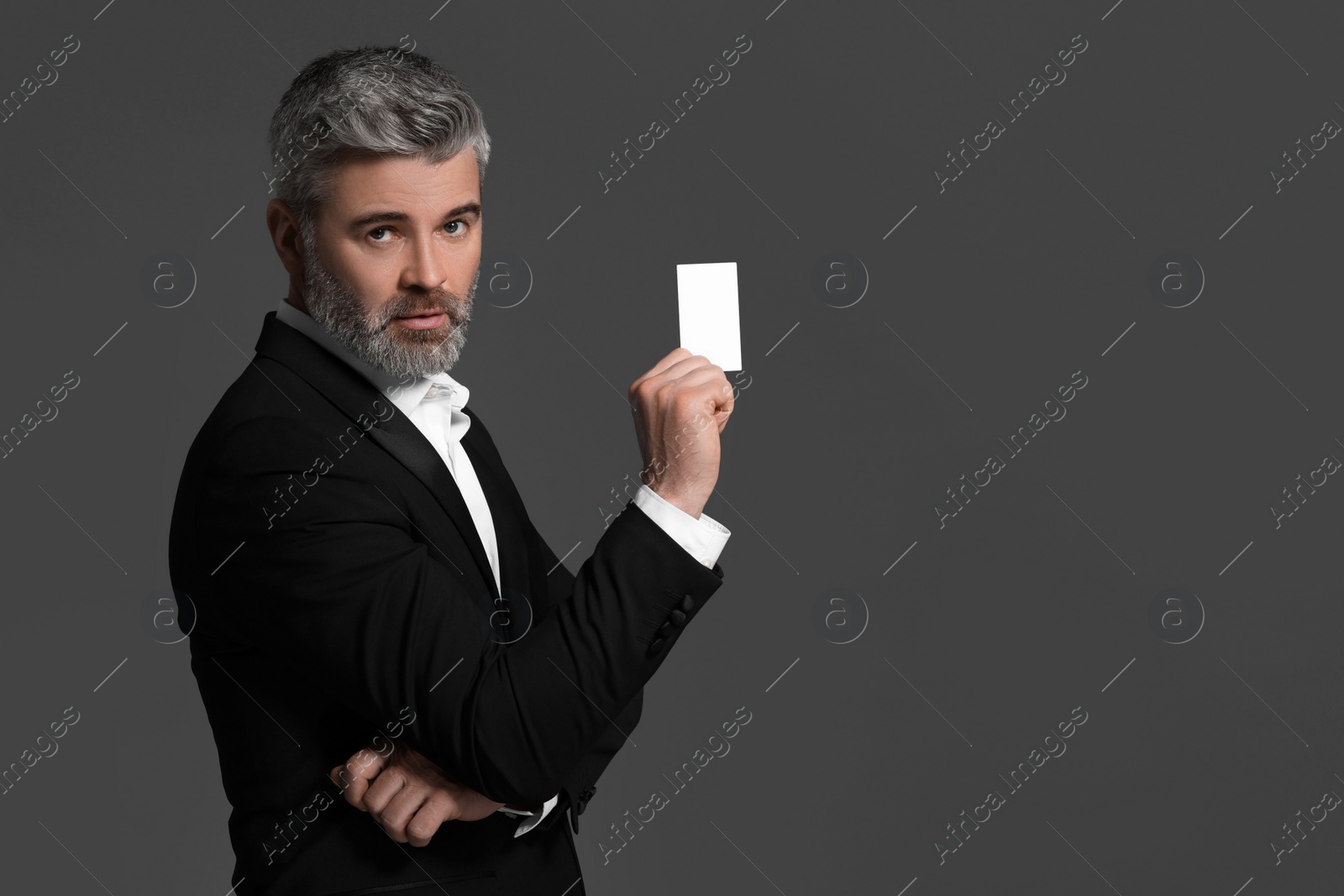 Photo of Handsome businessman holding blank business card on grey background. Space for text