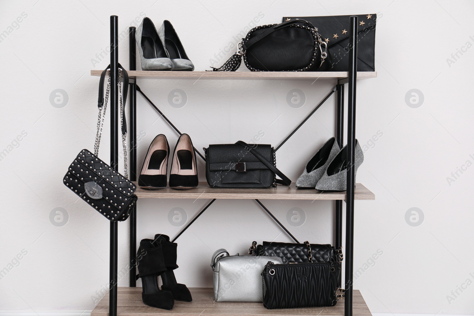 Photo of Shelving unit with stylish shoes and purses near white wall. Element of dressing room interior