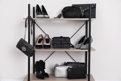 Shelving unit with stylish shoes and purses near white wall. Element of dressing room interior