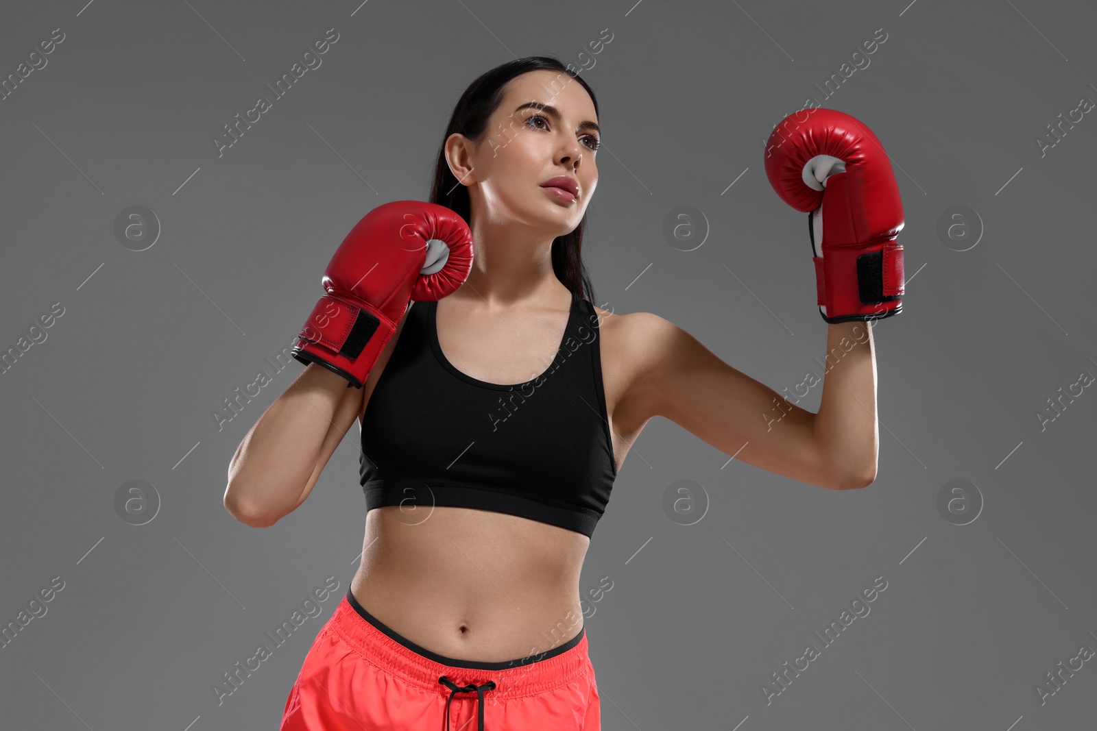 Photo of Beautiful woman in boxing gloves on grey background, low angle view