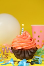 Delicious birthday cupcake with bright cream on yellow background