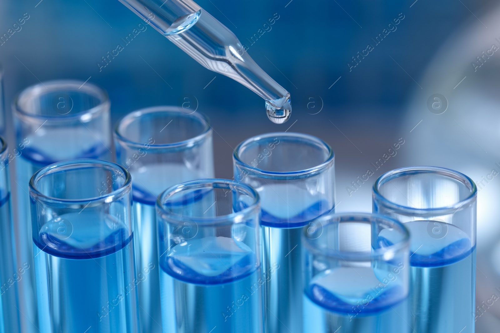 Photo of Dripping reagent into test tube on blurred background, closeup. Laboratory analysis