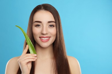 Photo of Young woman with aloe vera leaf on light blue background. Space for text