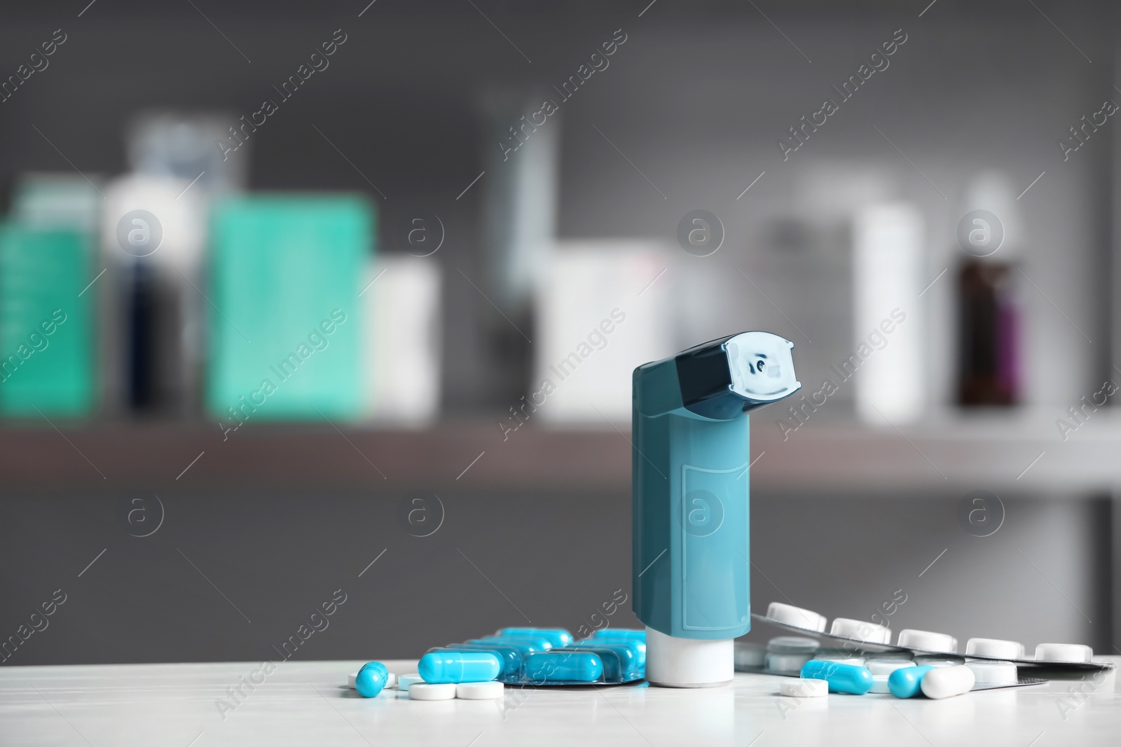 Photo of Asthma inhaler and pills on table against blurred background. Space for text