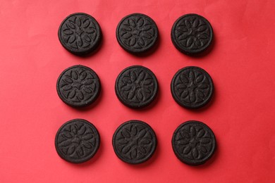 Photo of Tasty sweet sandwich cookies on red background, flat lay