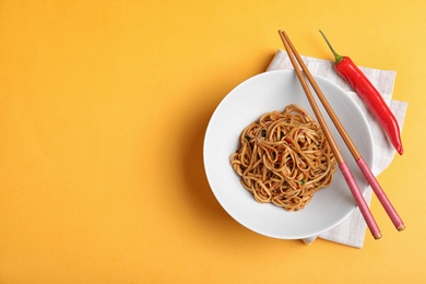 Cooked noodles served on orange background, flat lay. Space for text