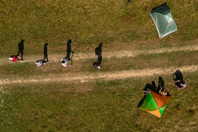 Image of Group of tourists near tents in campsite, top aerial view. Drone photography