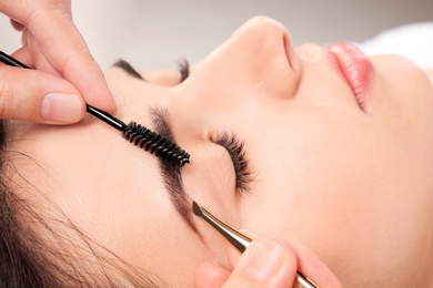 Photo of Young woman having professional eyebrow correction procedure in beauty salon, closeup