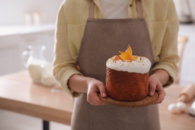 Young woman with traditional decorated Easter cake in kitchen, closeup. Space for text