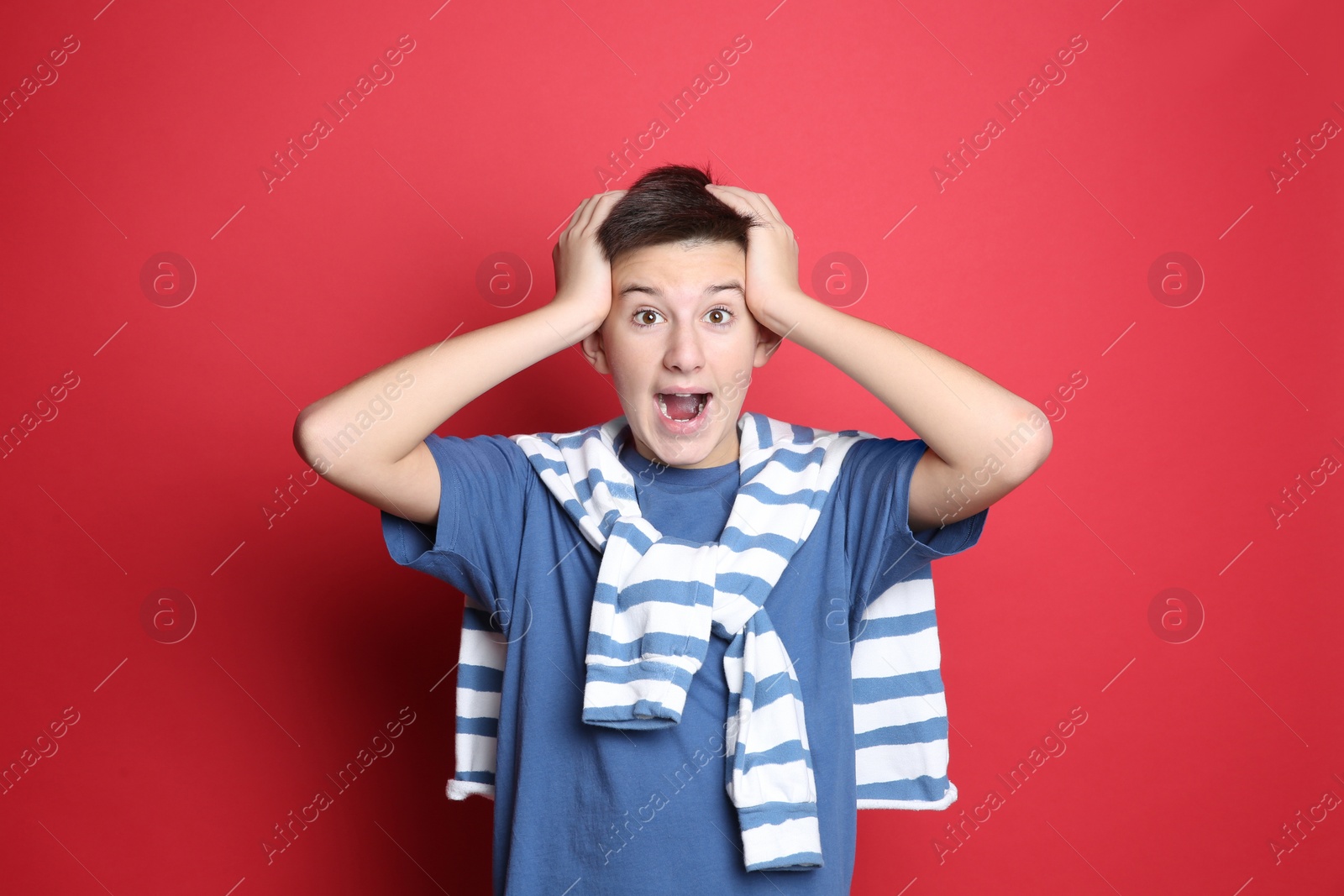 Photo of Portrait of emotional teenage boy on red background