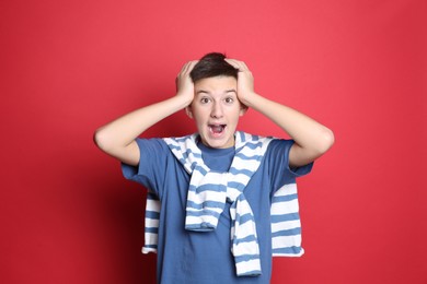 Photo of Portrait of emotional teenage boy on red background