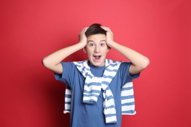 Portrait of emotional teenage boy on red background