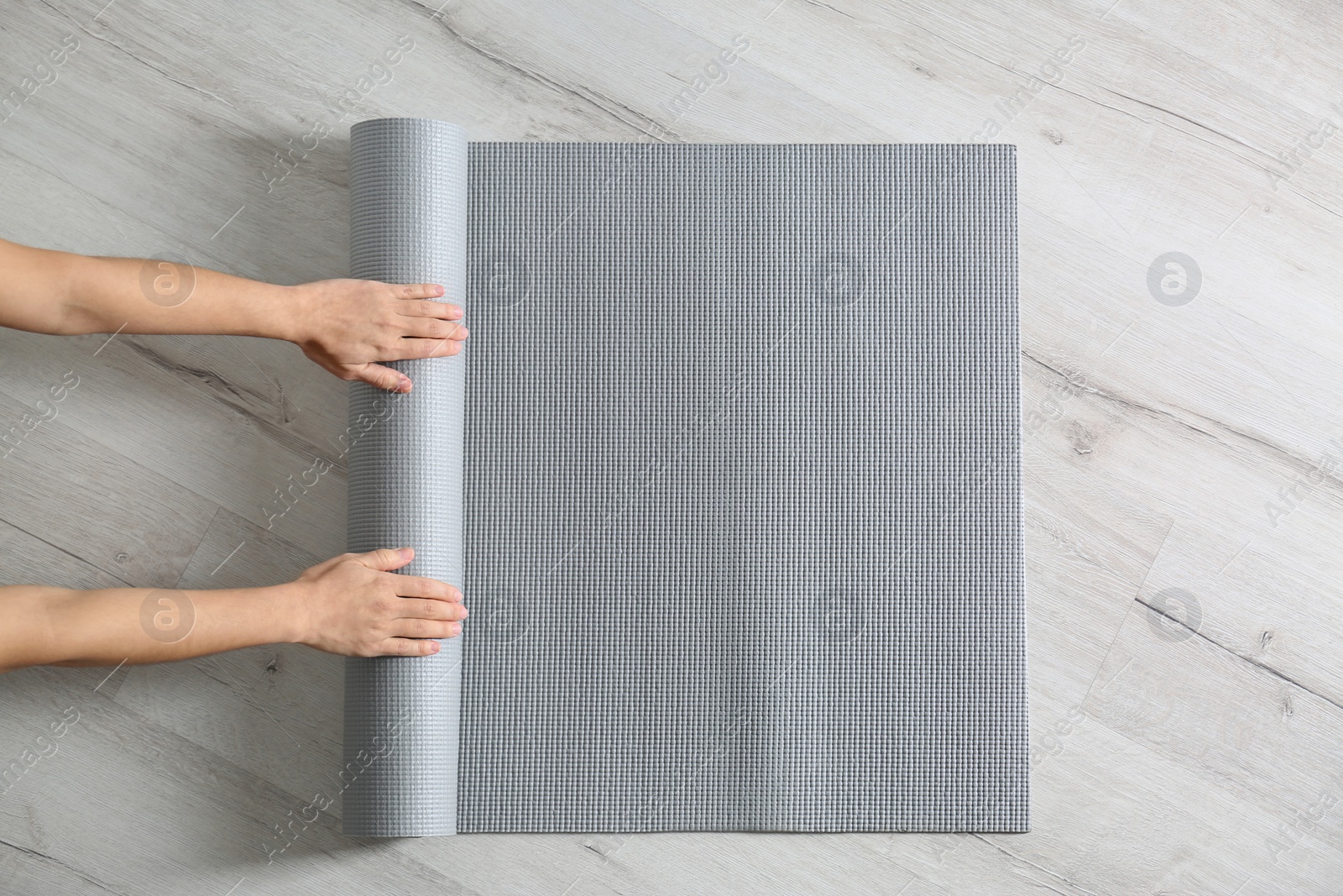 Photo of Woman rolling yoga mat on floor, top view. Space for text