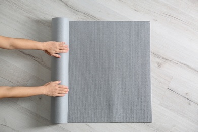 Woman rolling yoga mat on floor, top view. Space for text