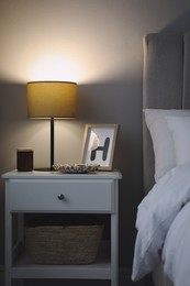 Photo of Stylish lamp and decor on white nightstand in bedroom