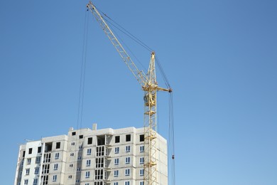 View of unfinished building and tower crane against blue sky