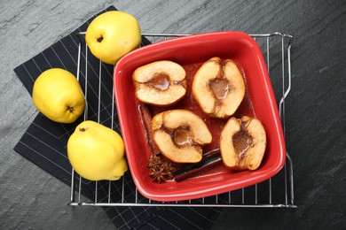 Tasty baked quinces with anise and honey in dish on black table, flat lay