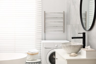 Photo of Stylish bathroom interior with heated towel rail and modern washing machine