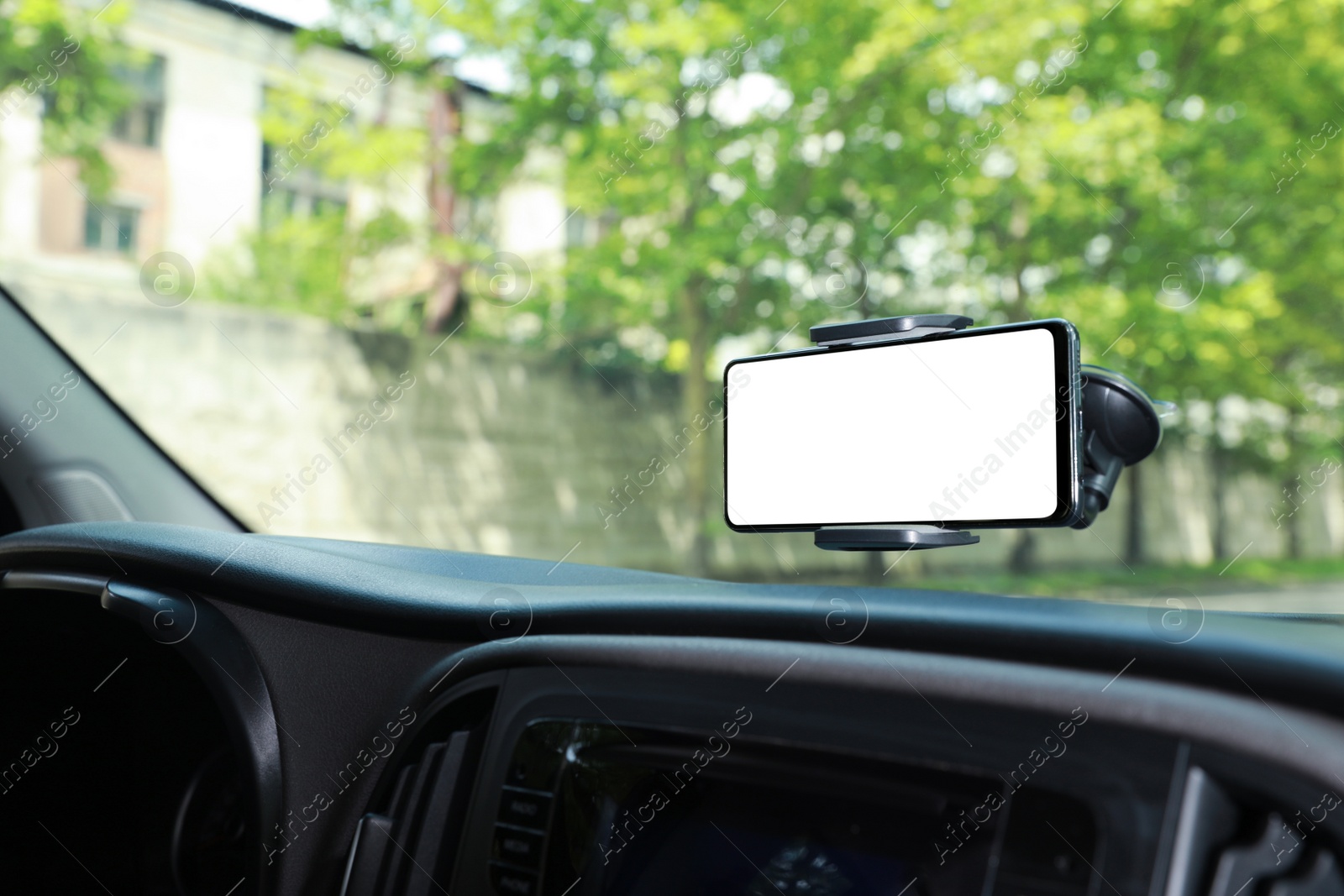 Photo of Car holder with modern mobile phone on windshield of automobile. Mockup for design