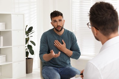 Photo of Psychotherapist working with drug addicted man indoors