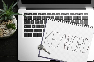 Photo of Composition with key, notebook and laptop on table, flat lay. Keyword concept