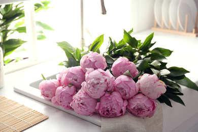 Photo of Bouquet of beautiful pink peonies in kitchen sink